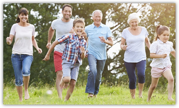 Kinder, Eltern und Großeltern rennen zusammen über eine Wiese