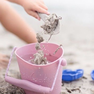 Faltbarer Silikon-Eimer wird von Kind mit Sand befüllt