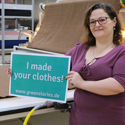 disana-Mitarbeiterin hält Schild mit der Aufschrift "I made your clothes!" hoch.