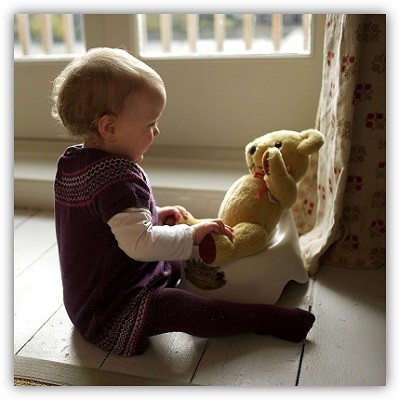 Kind setzt seinen Teddybär auf ein Töpfchen