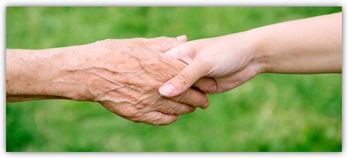 Eine ältere und eine jüngere Person geben sich die Hand