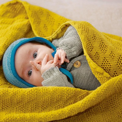 Baby eingewickelt in eine Puckdecke von Disana aus Merinowolle