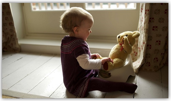 Kind setzt seinen Teddy aufs Töpfchen