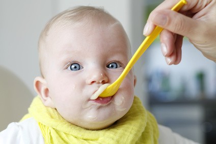 Baby mit einem Löffel Fruchtpüree im Mund
