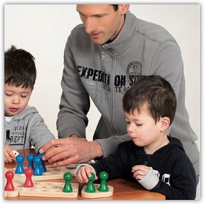 Vater spielt mit seinen 2 Söhnen mit einem XXL-Ludo-Spiel