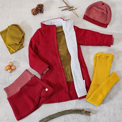 Herbst-Outfit: roter Wollmantel mit gelber Leggings, rotem Rock, roter Mütze und ockerfarbenem Cardigan 