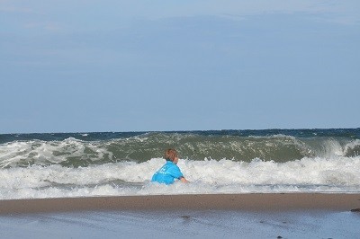 Junge mit hellblauem Bade-T-Shirt in den Wellen der See