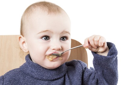 Baby isst mit einem Löffel Breikost.