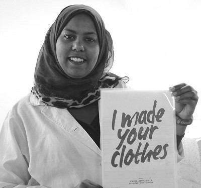 Arbeiterin bei PWO hält Schild hoch mit der Aufschrift "I made your clothes"