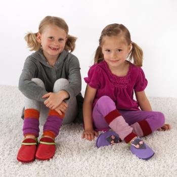 Zwei Mädchen sitzen auf dem Boden und tragen Bio-Schurwoll-Stulpen von Pololo