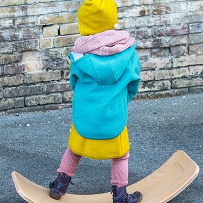 Kind steht draußen dick eingepackt auf einem Balance-Board