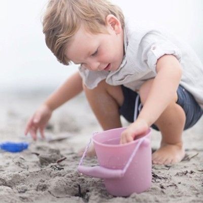 Junge spielt mit dem rosa Eimer von Scrunch im Sand