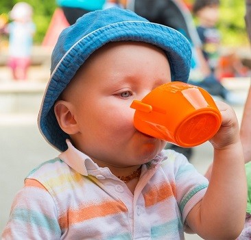 Kind trinkt einhändig aus dem Doidy Cup in Orange