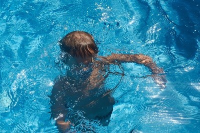 Junge ist in einem Schwimmbecken mit dem Kopf unter Wasser