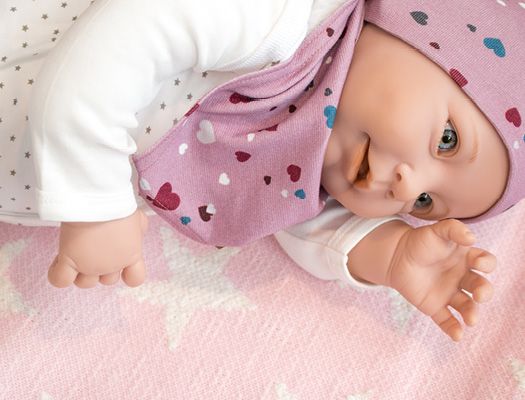 Babypuppe auf einer rosa Decke mit weißen Sternen