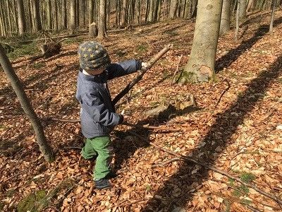 Junge spielt im Wald mit Stöcken.