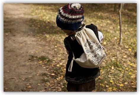 Kind läuft draußen mit dem Wooden-Story-Sack auf dem Rücken herum