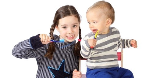 Große Schwester und kleines Geschwisterkind putzen sich zusammen die Zähne.