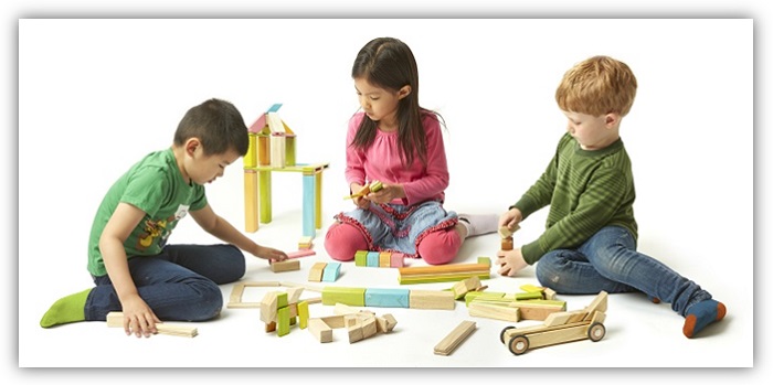 Zwei Jungs und ein Mädchen sitzen auf dem Boden und spielen mit den Magnet-Bausteinen von tegu