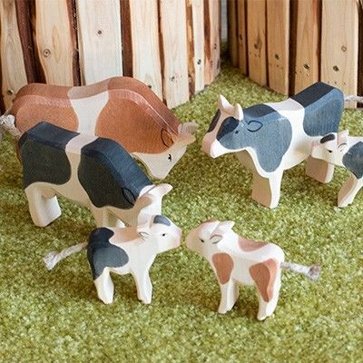 Eine Szenerie aus Holzfiguren zeigt eine tierische Familie bestehend aus Kalb, Kuh und Stier. 