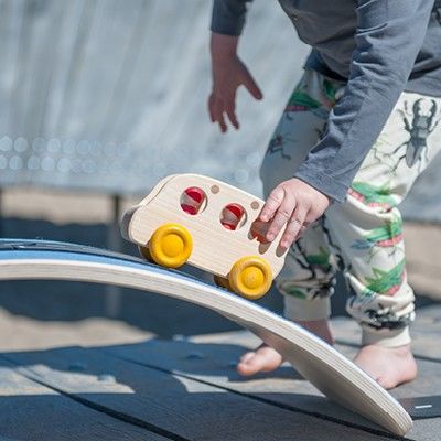 Kind lässt ein Holzauto über das Wobbel Board fahren, das als Brücke dient
