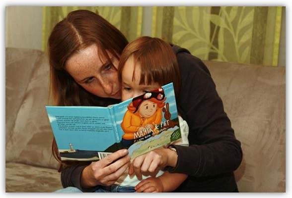 Frau hat Kind auf dem Schoß und ließt das Buch "Martha und Piet" vom neunmalklug Verlag vor