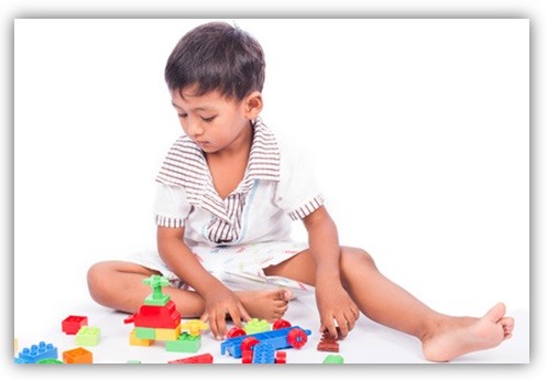 Kind spielt mit Bausteinen auf dem Boden