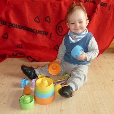 Kind spielt auf dem Boden mit unbedenklichem Stapel-Spielzeug
