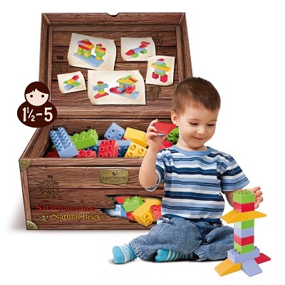Junge sitzt mit den Bausteinen spielend vor der Kiste im Schatztruhen-Look