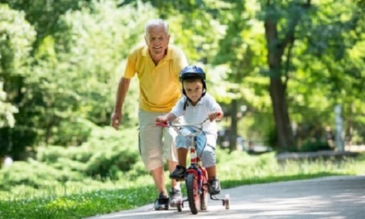 Opa hilft seinem Enkel beim Fahrradfahren