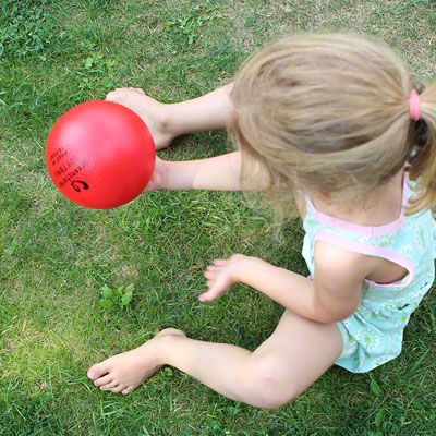 Mädchen spielt mit rotem Softball von greenstories