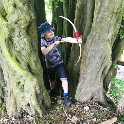 Junge spielt im Wald mit Pfeil und Bogen