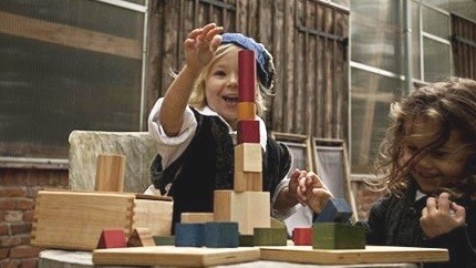 Zwei Kinder spielen begeistert mit den Holzbausteinen von Wooden Story.