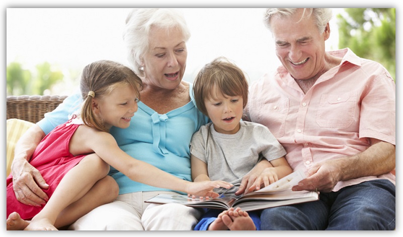 Oma und Opa lesen ihren beiden Enkelkindern ein Buch vor.