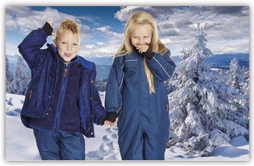Junge und Mädchen in Schneeanzügen vor Schneelandschaft
